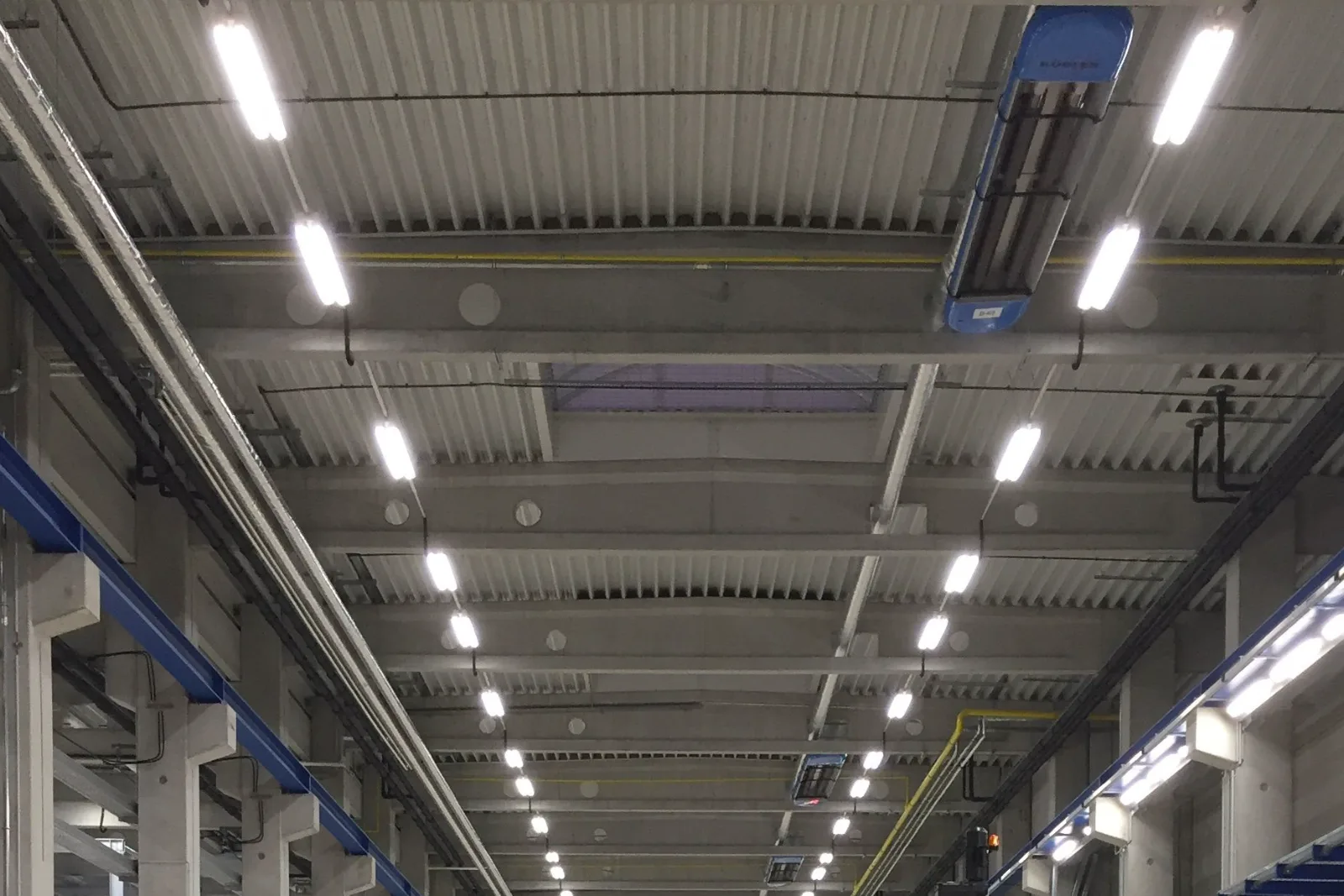 Rows of lit linear LED batten lights running the length of a high commercial ceiling.
